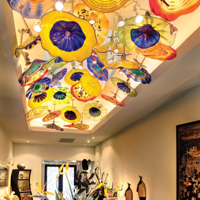 a glass lighting installation that looks like many large colorful flowers attached to the ceiling.